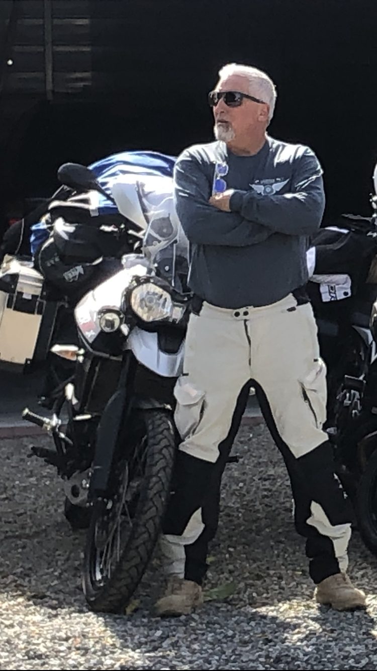Rick Hopper standing next to his motorcycle in riding gear